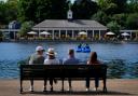 Morning visitors observe pedalo riders by the Serpentine in Hyde Park, London