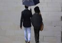 A couple walking in the rain in the City of London.