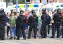 Police officers in riot gear standing in front of protestors