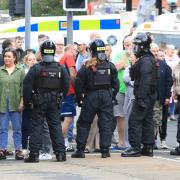 Police officers in riot gear standing in front of protestors