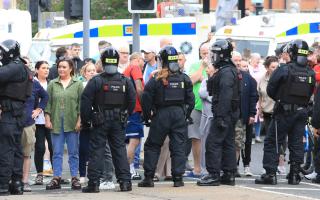 Police officers in riot gear standing in front of protestors